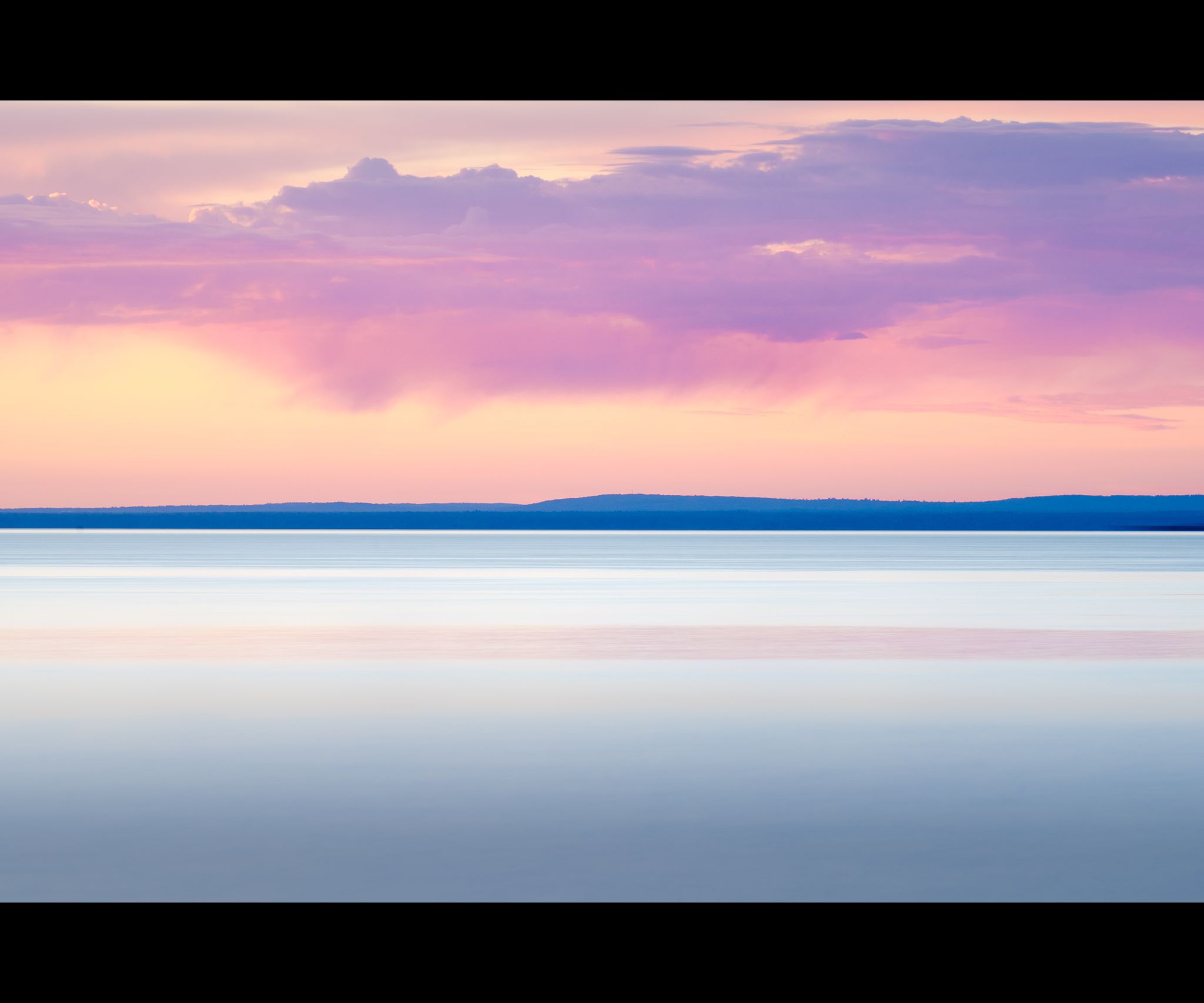 Long exposure of Lake Superior at sunrise with purple rain clouds and pinks and blues