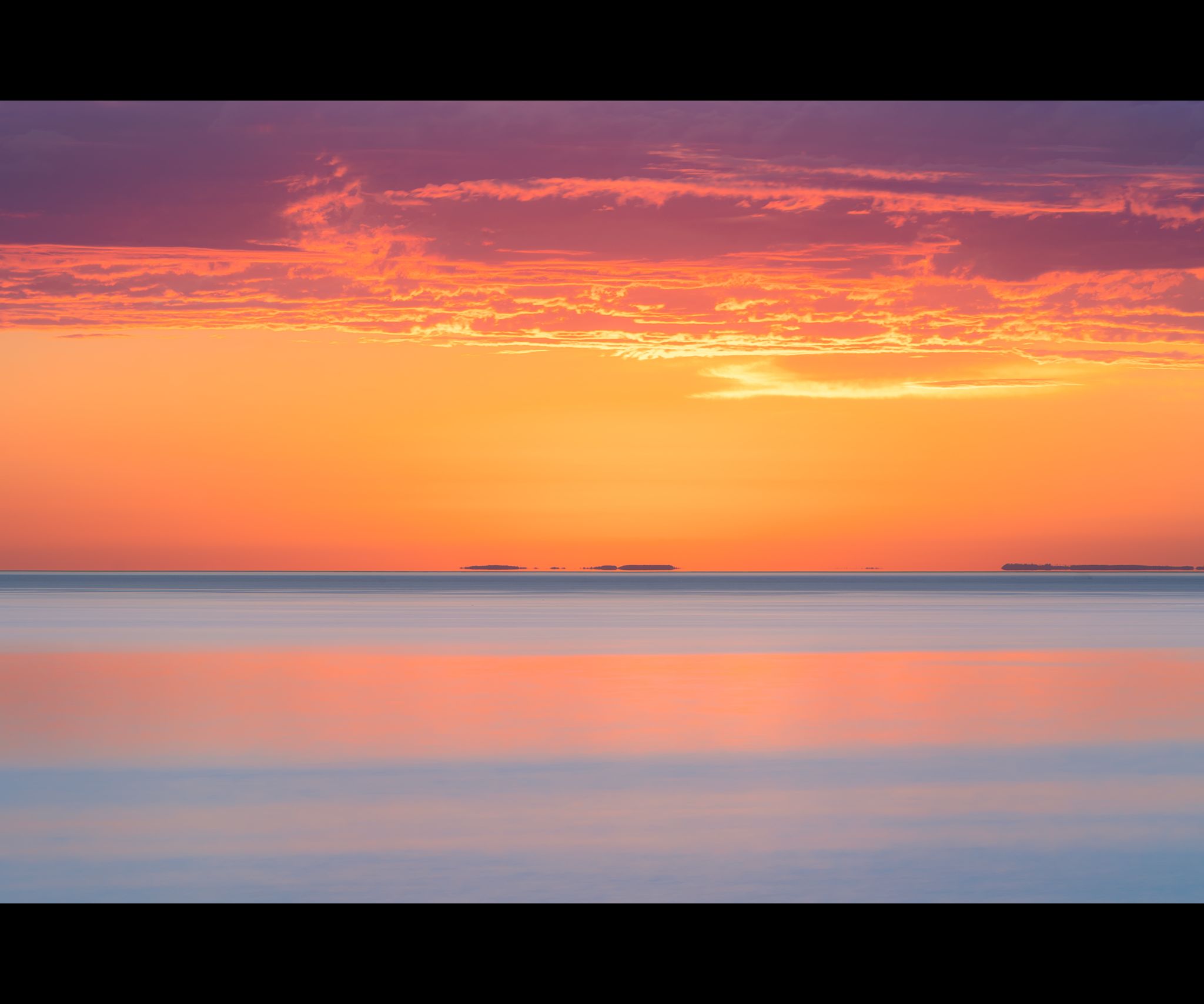 Long exposure of Lake Superior at sunrise with purple rain clouds and pinks and blues