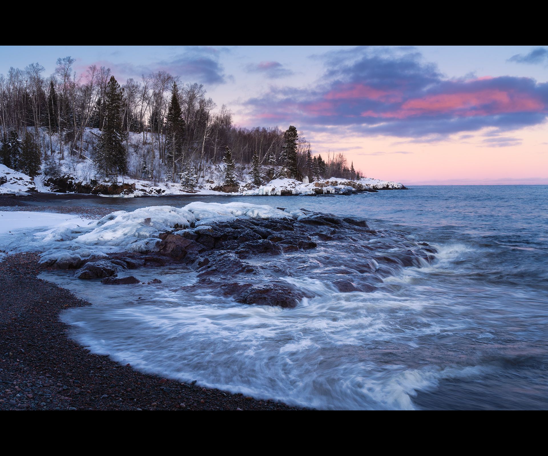 Snow-covered Lake Superior beach at sunset with pink and purple clouds