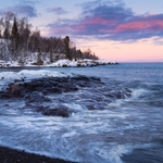 Snow-covered Lake Superior beach at sunset with pink and purple clouds