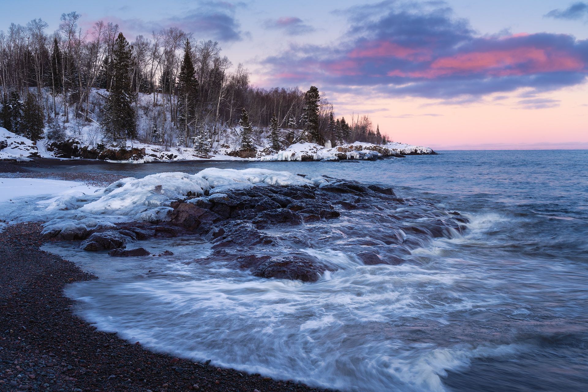 Snow-covered Lake Superior beach at sunset with pink and purple clouds